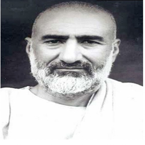 Portrait of Khan Abdul Ghaffar Khan in middle life, in white clothing with a short grey beard, looking directly at the camera.