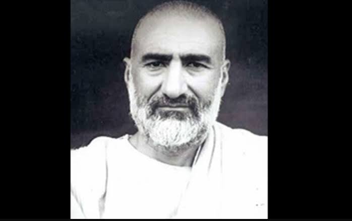 Portrait of Khan Abdul Ghaffar Khan in white homespun against a dark background, facing the camera.